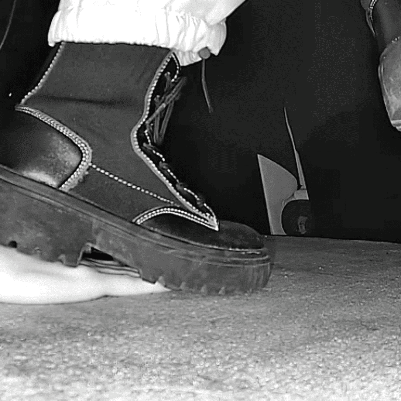Woman unaware steps on hand with chunky-heeled black ankle boots in cinema thumb 2