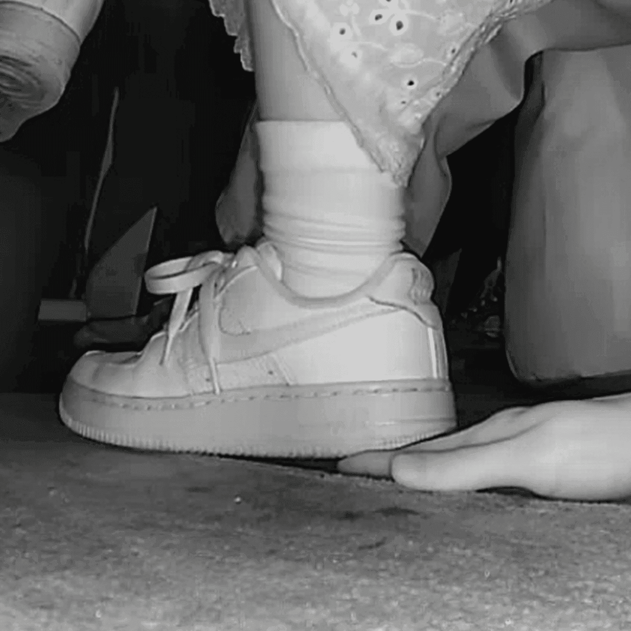 Woman in long skirt and white Nike Air Force sneaker unaware hand trample at the cinema